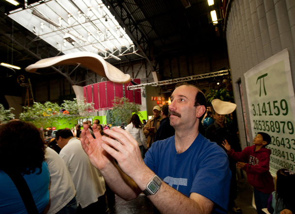 Exploratorium physicist Ron Hipschman perfects his pizza pie–tossing technique—one of many pi-inspired activities at the museum's annual Pi Day celebrations.