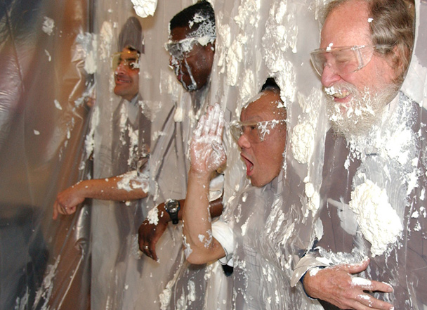 Museum staff members volunteer as targets for Pi Day's annual pie throwing contest, which includes a lesson in physics.