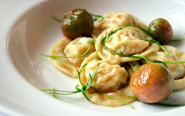 A lunch entrée of homemade lobster-stuffed ravioli with black cherry tomatoes tossed with beurre noisette and garnished with fennel microgreens.